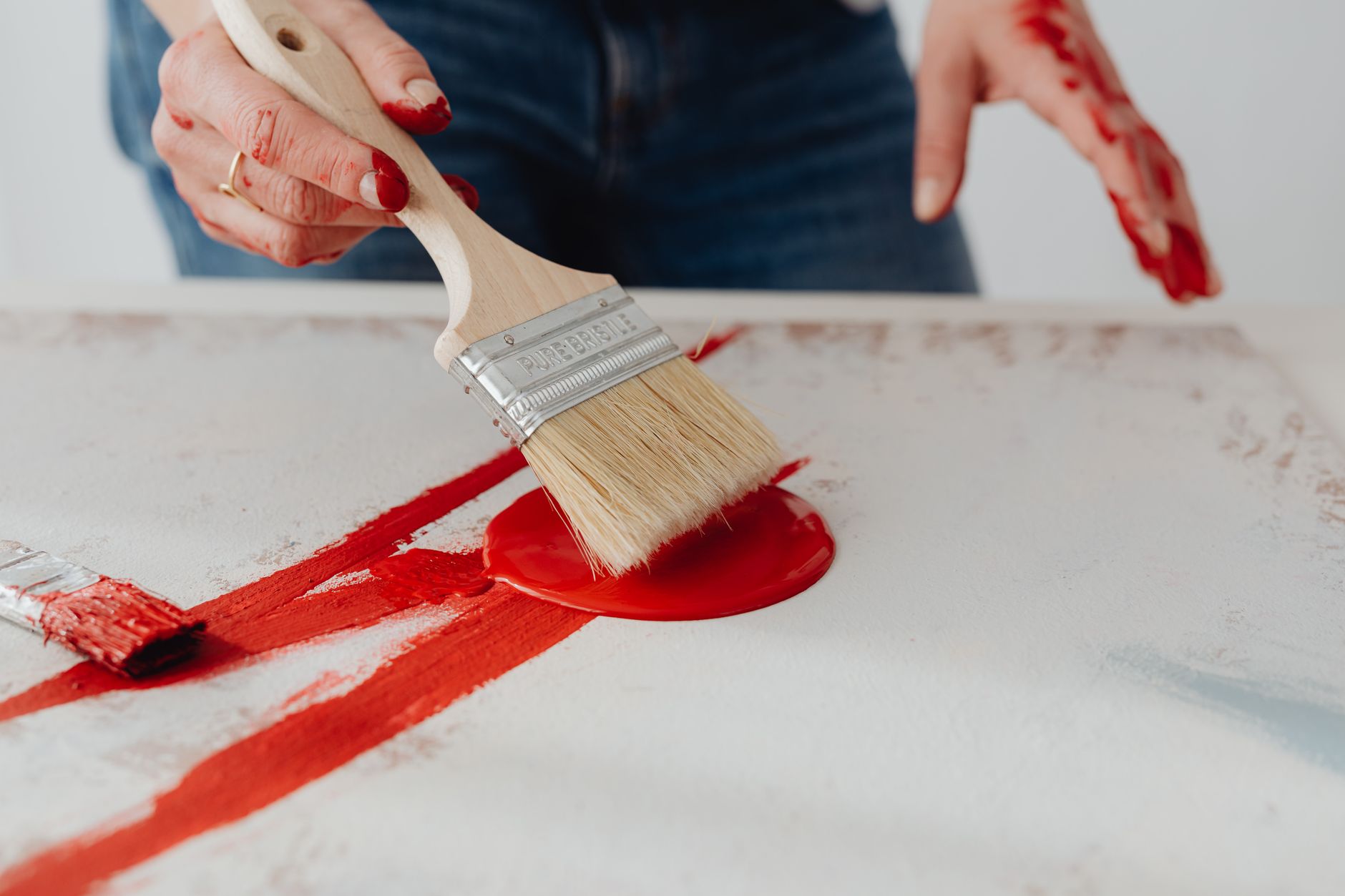Una persona humedeciendo una brocha de pintura con agua antes de usarla para preparar las cerdas y facilitar la limpieza posterior.