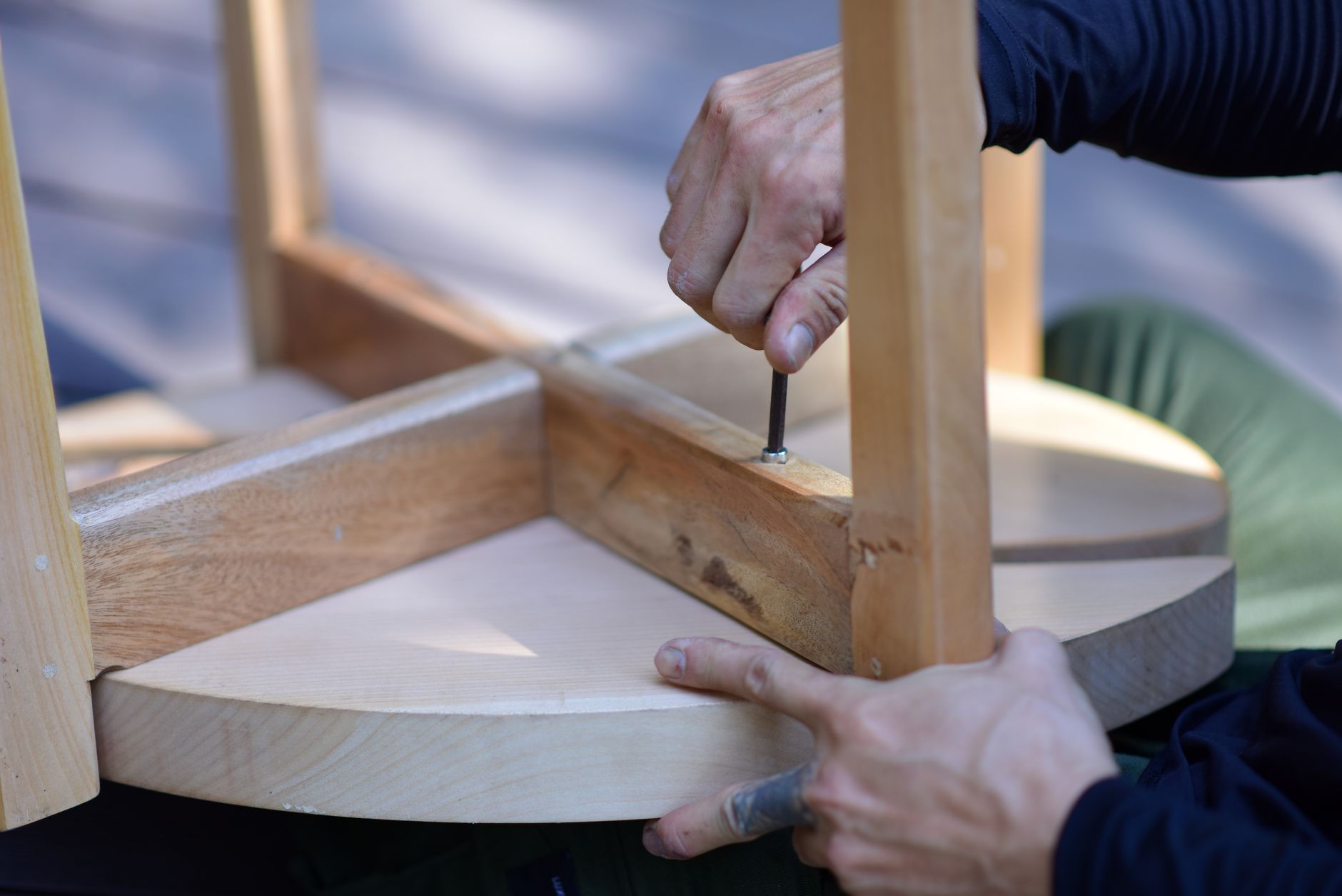 Manos lijando un mueble de madera antiguo, con herramientas y botes de pintura alrededor, simbolizando la restauración DIY