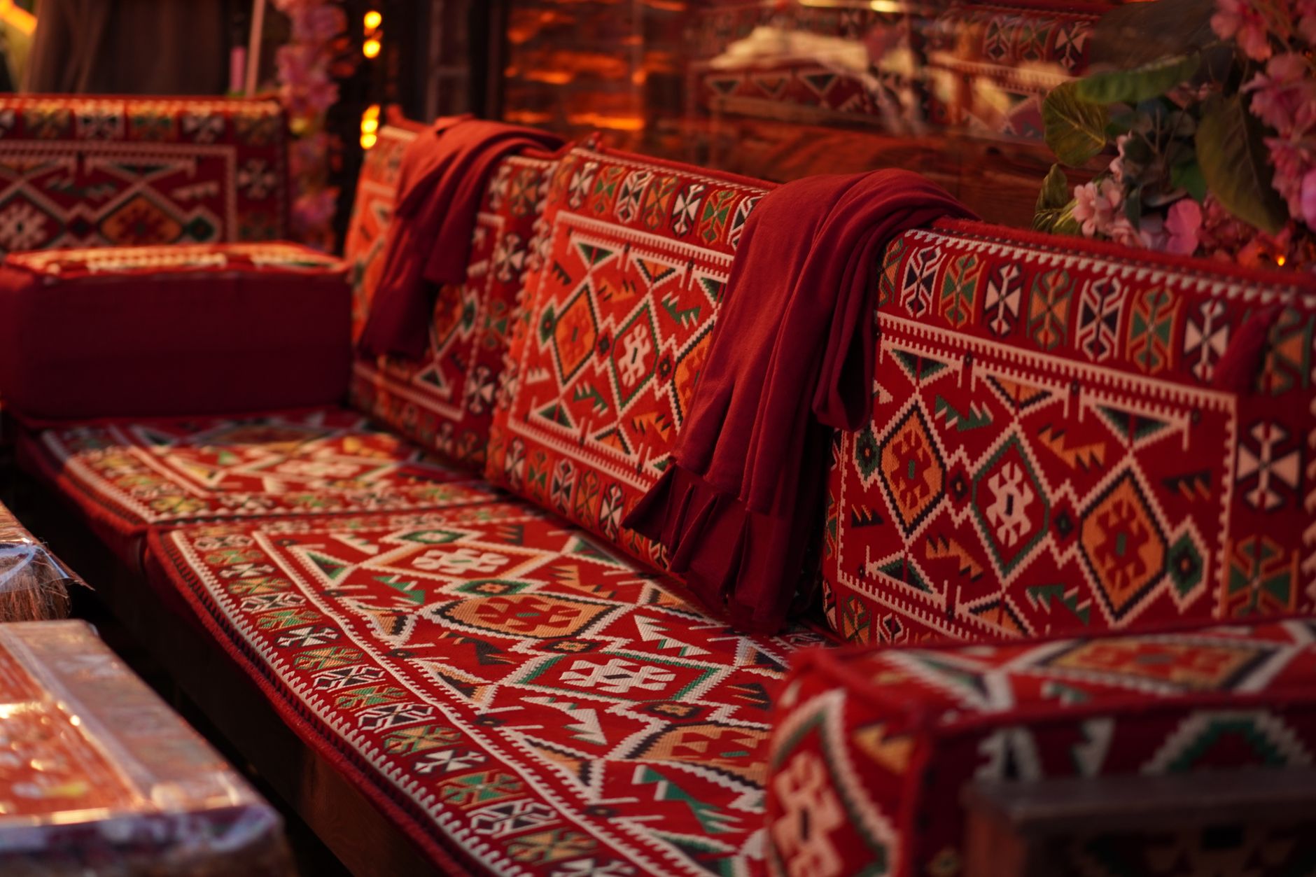 Un salón acogedor con una alfombra suave, cojines mullidos y una manta de punto sobre un sofá, creando un ambiente cálido y texturizado.
