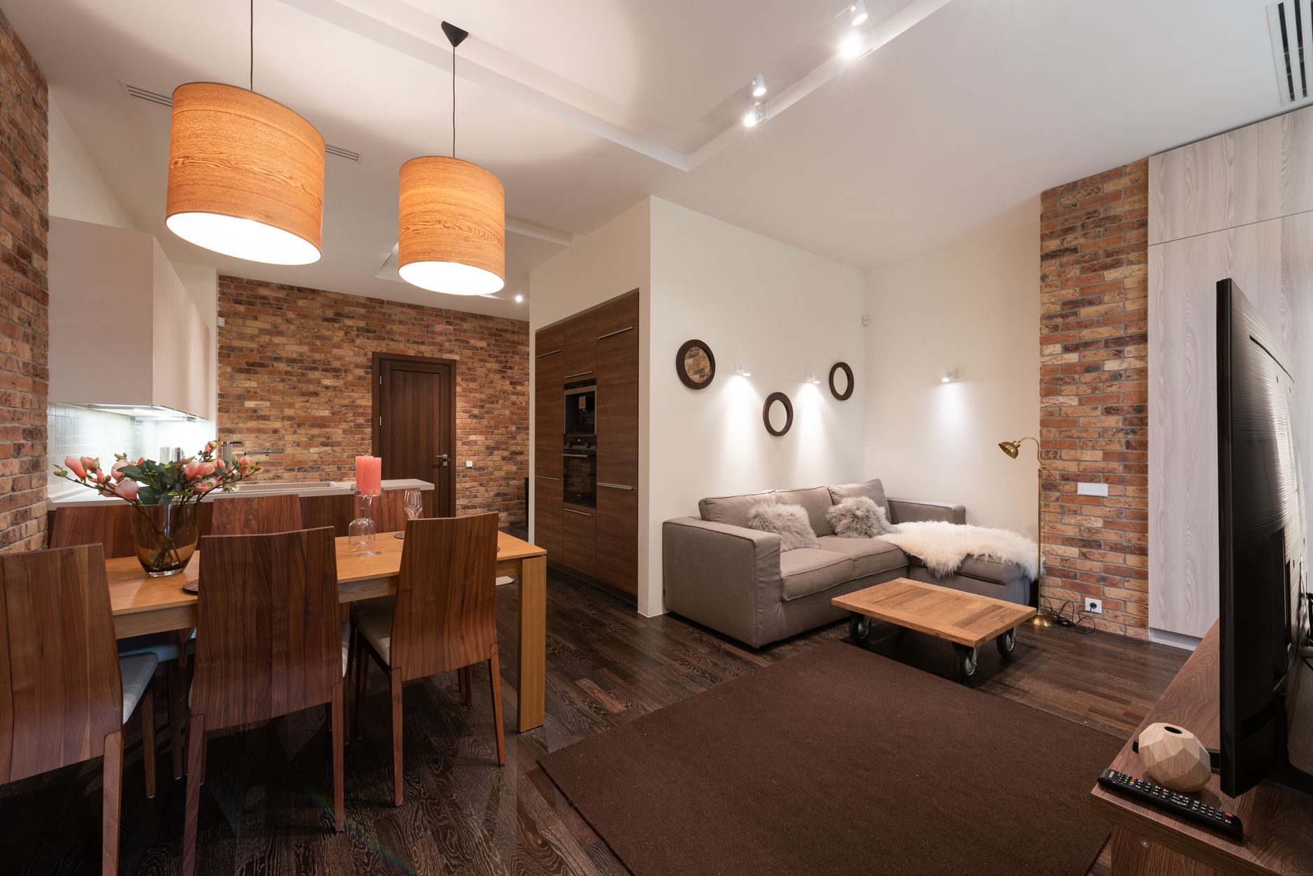 Un dormitorio moderno con iluminación ambiental del techo, una lámpara de lectura junto a la cama y luces de acento que destacan una obra de arte, mostrando la iluminación por capas.