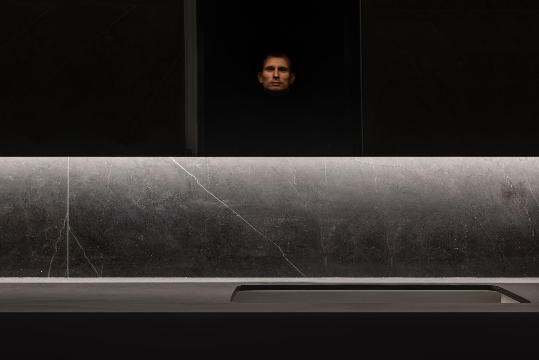 Interior de baño con paredes en tonos oscuros, grifería de metal envejecido y texturas ricas.