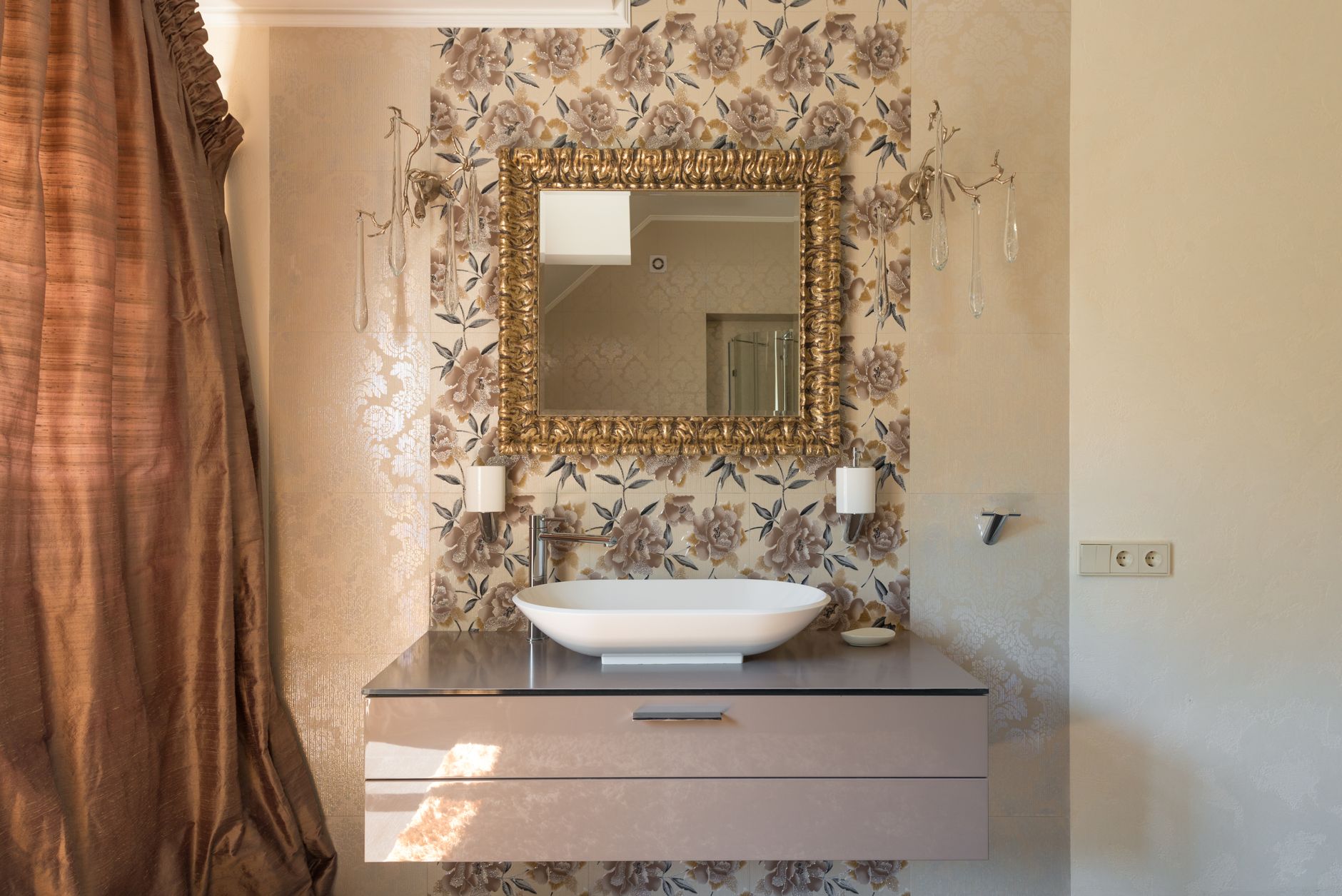 Tocador de baño con espejo ornamentado, jarrones de boticario y accesorios de estilo clásico.